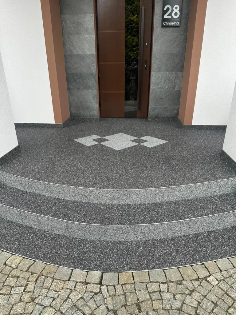 Kamienny dywan na półokrągłych schodach i podeście wejściowym