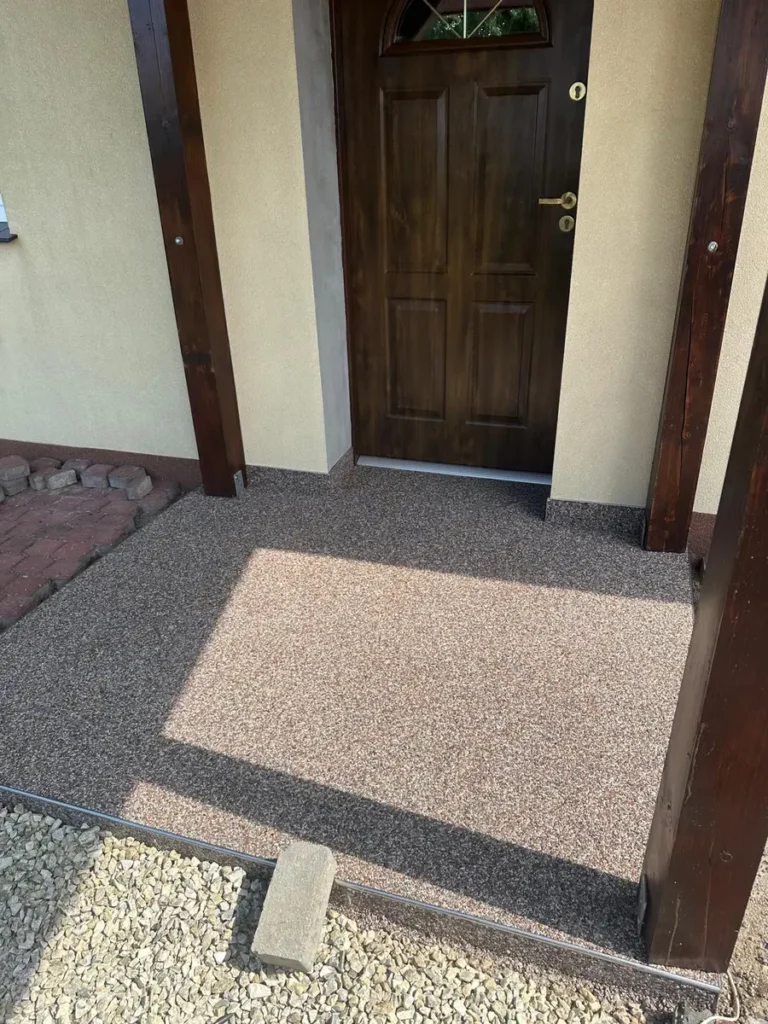 Taras z kamiennym dywanem przy wejściu do domu